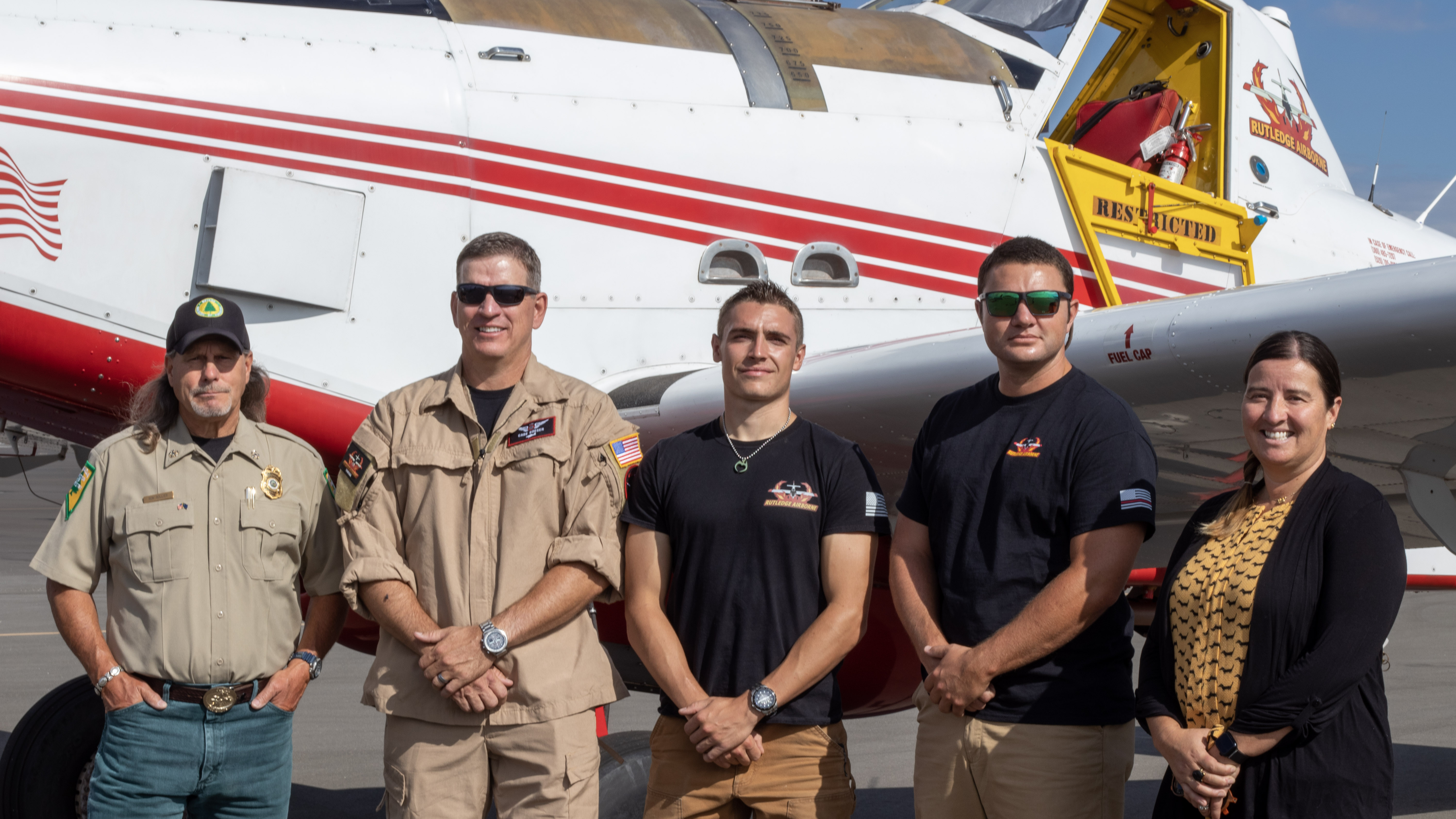 group photo of NDF and Rutledge Airborne Applications posing in front of an aircraft. From left to right, Ron Bollier, Cade Boeger, Wyatt Jourdain, Tanner Bowers, and State Forester Firewarden Kacey KC